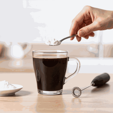 C8 MCT oil powder being added to coffee in a glass mug.