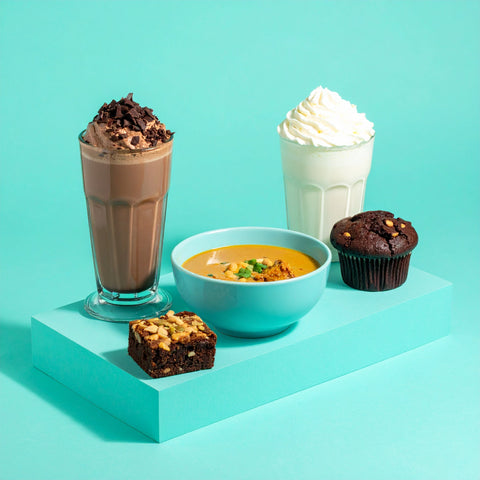 Ultimate Pantry Pack with shakes, soup, muffin, and brownie on a blue stand.