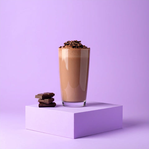 Chocolate Collagen Keto Shake with chocolate pieces on a purple platform.
