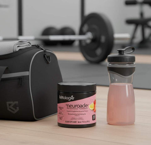 Neuroade™ Strawberry Lemonade hydration mix container and shaker bottle with light pink drink on gym floor next to gym bag and weights