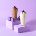 Protein Power Stack featuring chocolate and vanilla shakes with dumbbells on a purple background.